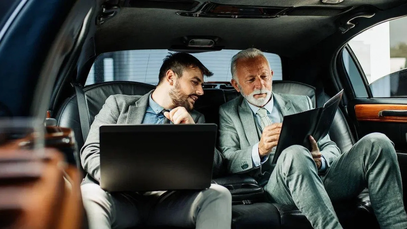 two business man in black car discussing