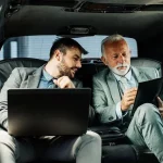 two business man in black car discussing